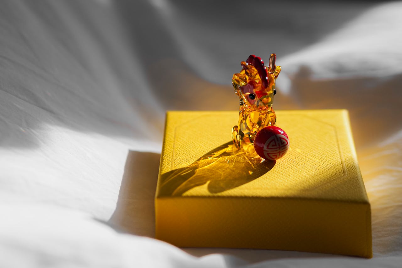 Crystal dragon figurine on box, casting shadows in natural light.